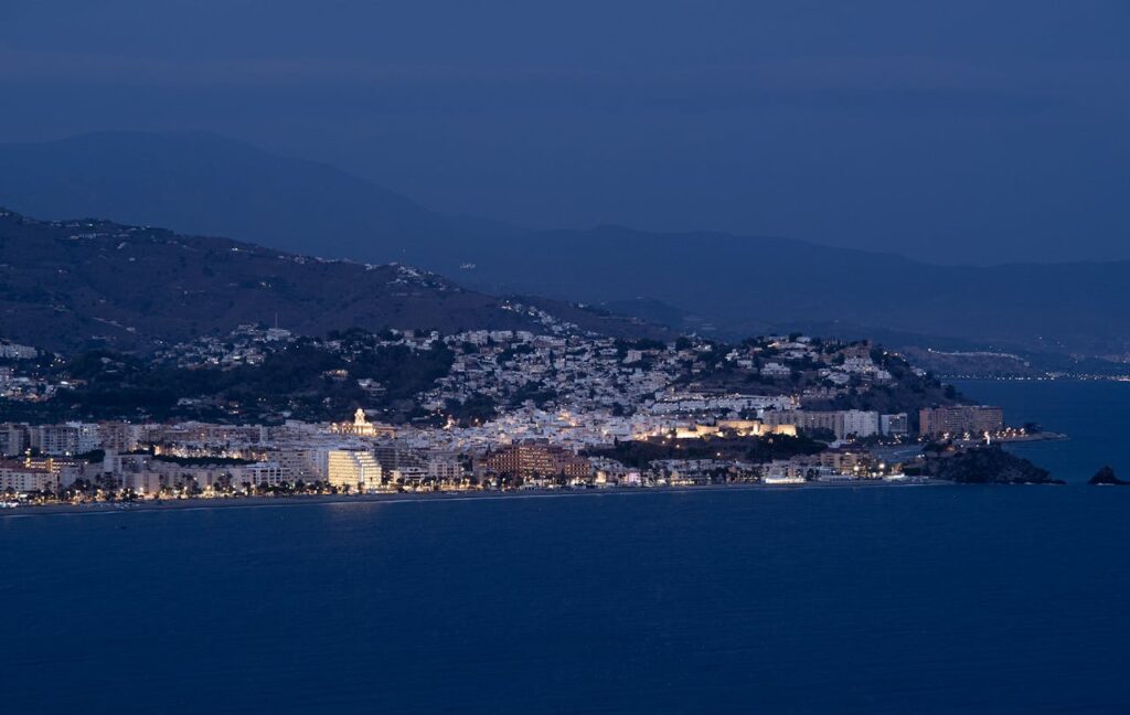 Stunning view of Granada's coastline and illuminated cityscape at night, capturing natural beauty and vibrant city life.